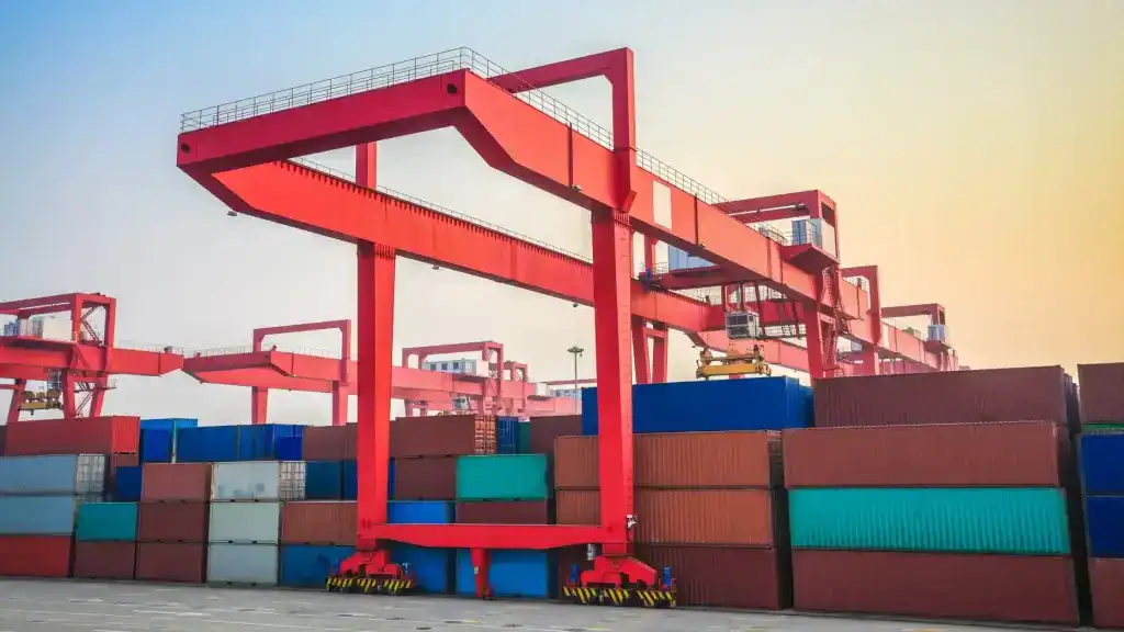Container crane at port with stacked shipping containers for freight logistics.