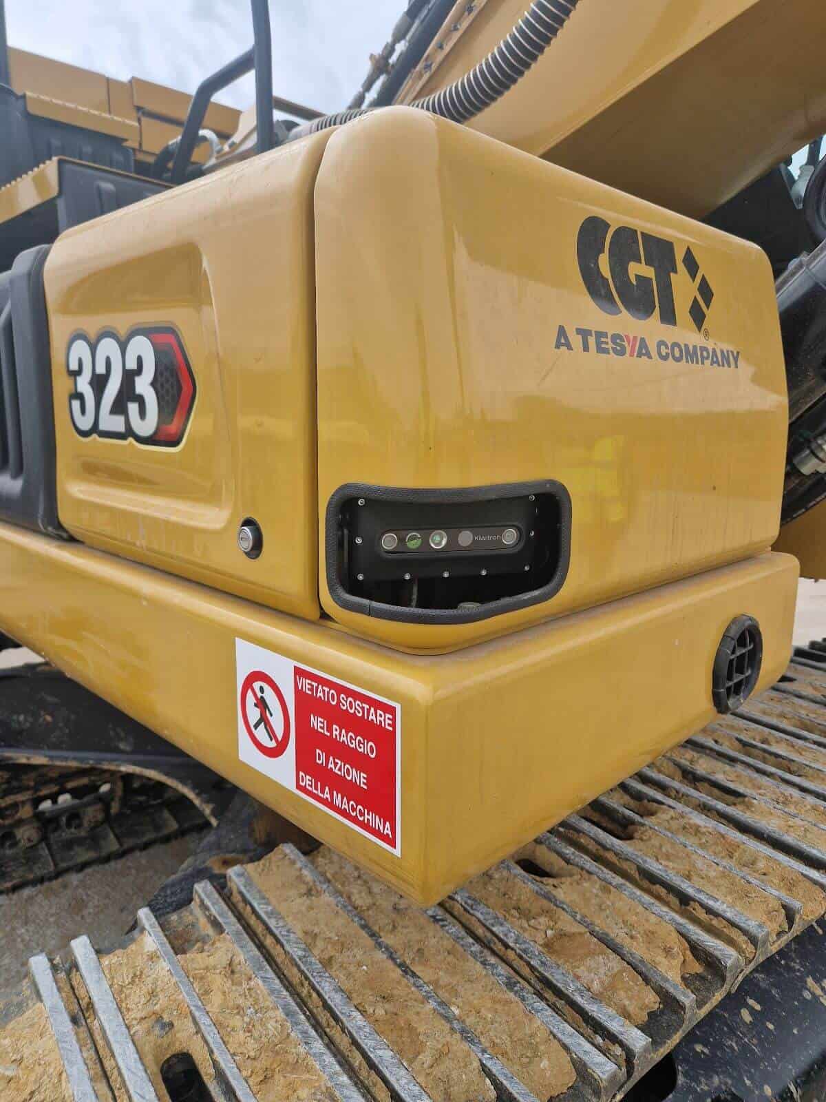Heavy construction excavator with CAT 323 model and safety warning label.
